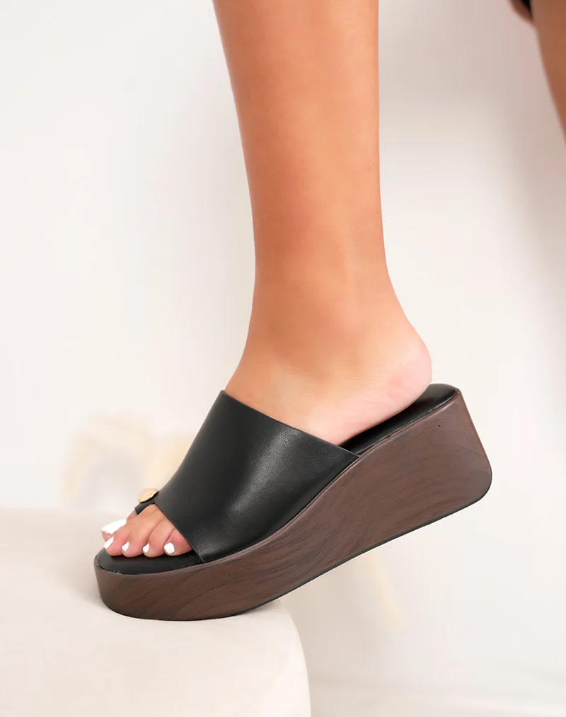 Mules compensées femme noires élégantes avec bijou doré et semelle effet bois